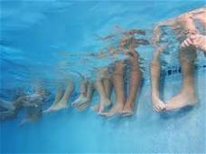 Legs lined up beneath the water of swimming pool